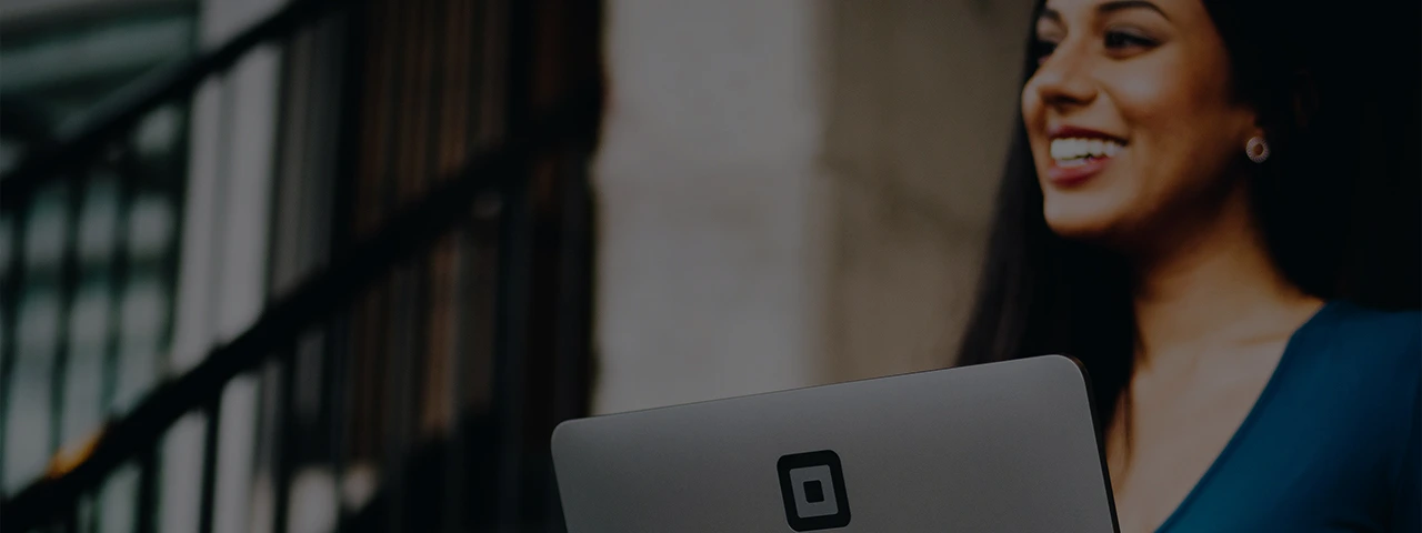 Female IT consultant smiling in front of her laptop sitting down.