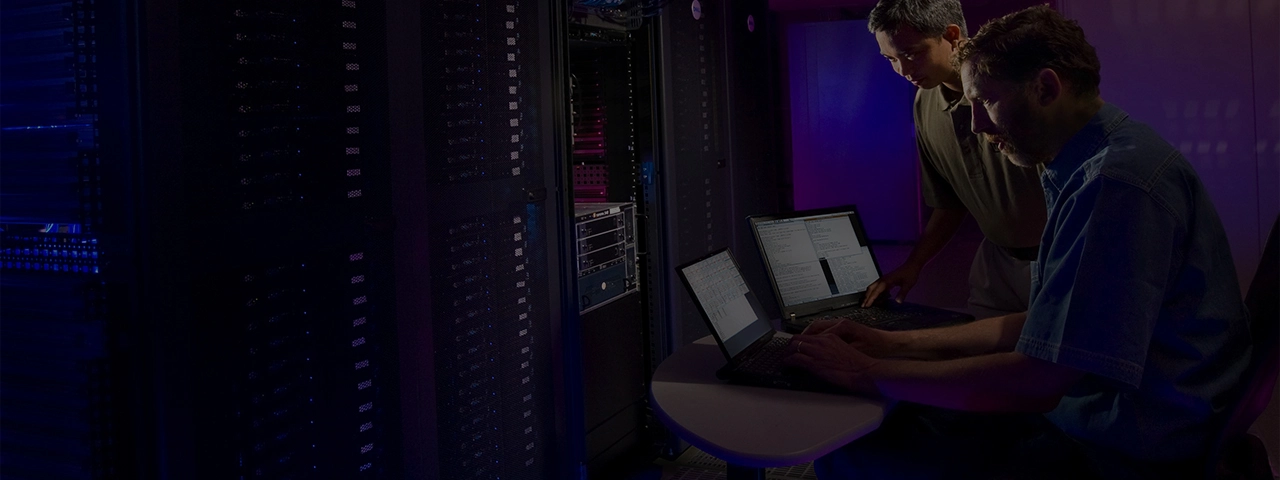 Two employees at a network support company analyzing the network with laptops.